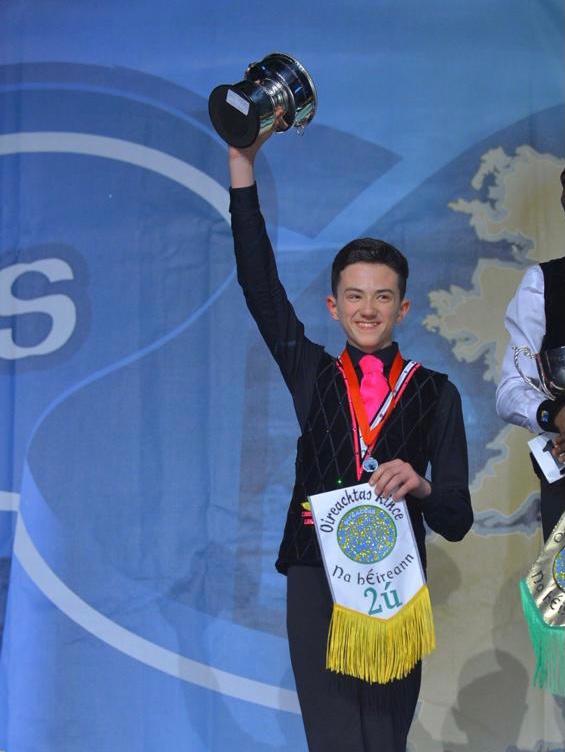 A Céim Óir dancer lifting his trophy at the All Ireland Championships