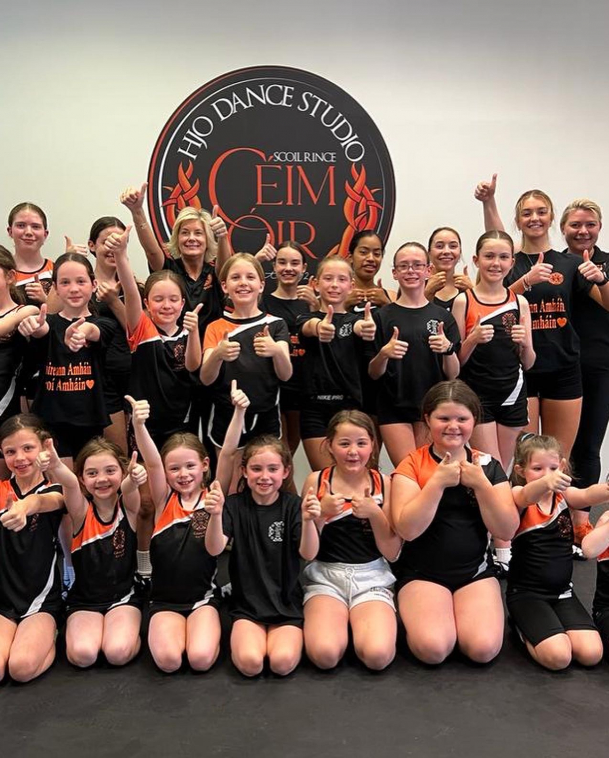 Céim Óir dancers giving a thumbs up under the HJO Dance Studio badge